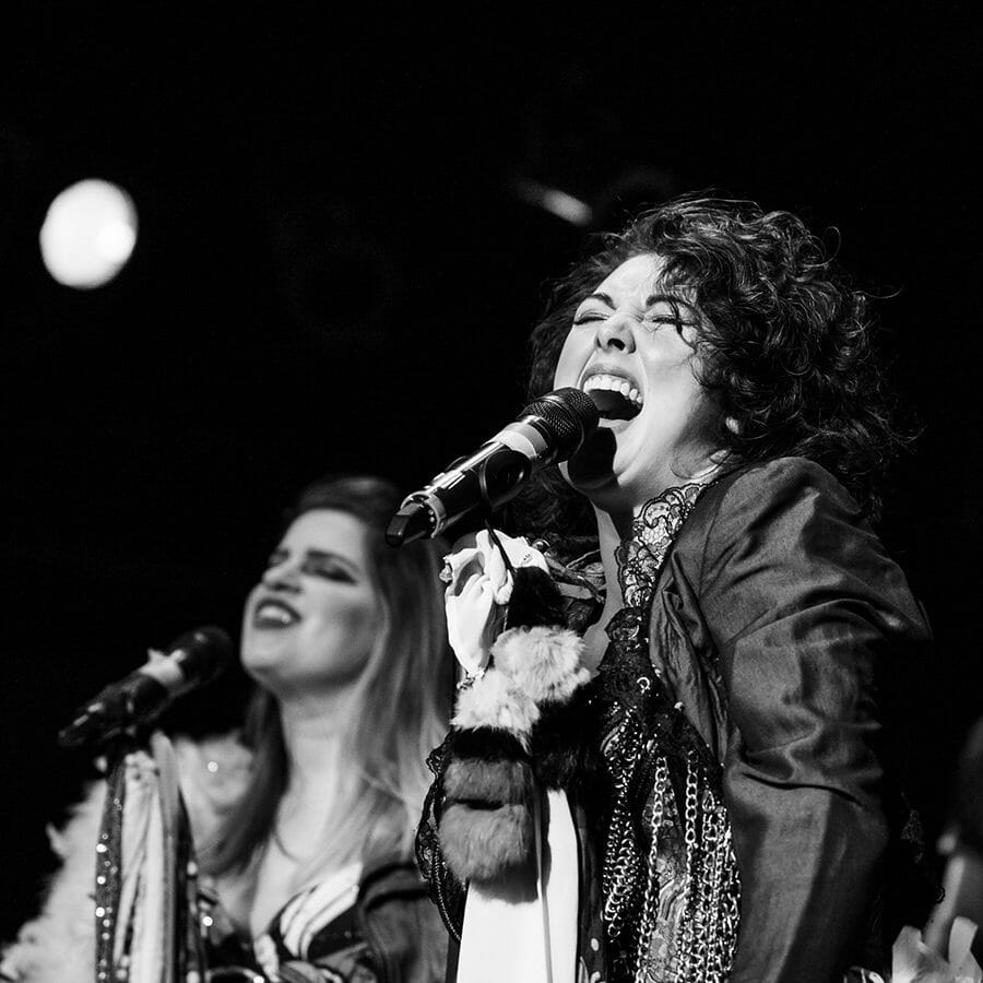 Black and white photo of two women singing into microphones.