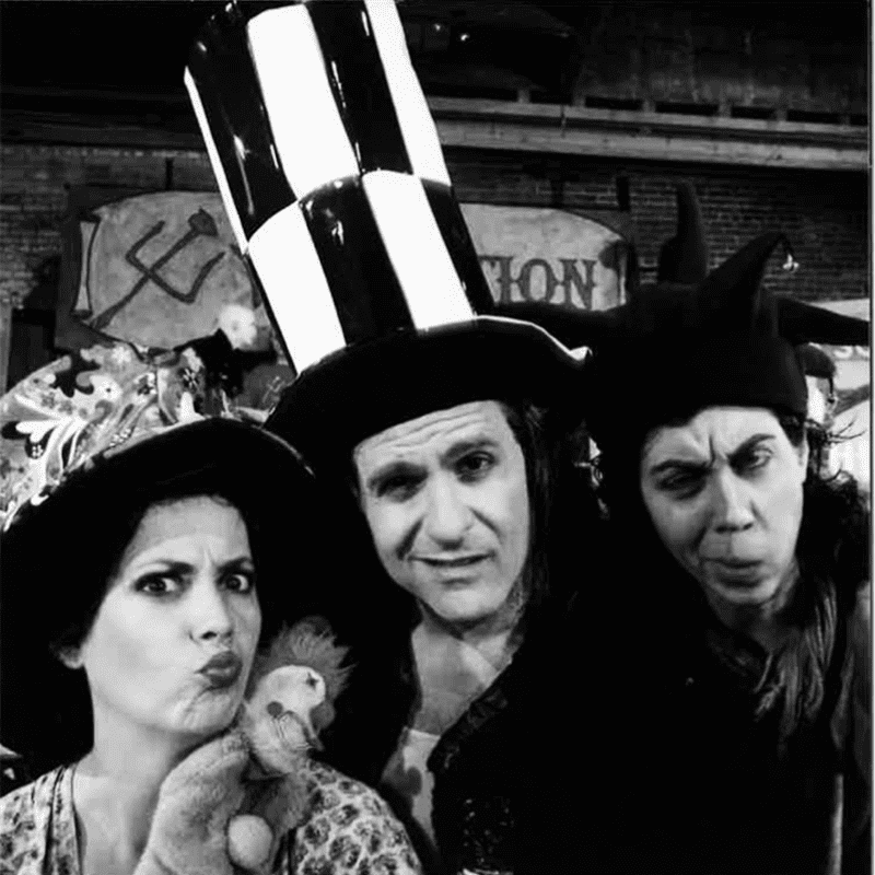 Three people dressed up in top hats posing for a photo with a touch of history.