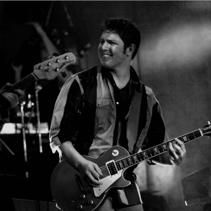 Historical black and white photo of a man playing a guitar.